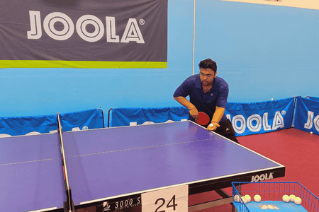 Coach Subhum Kundu demonstrates a strong table tennis serve.