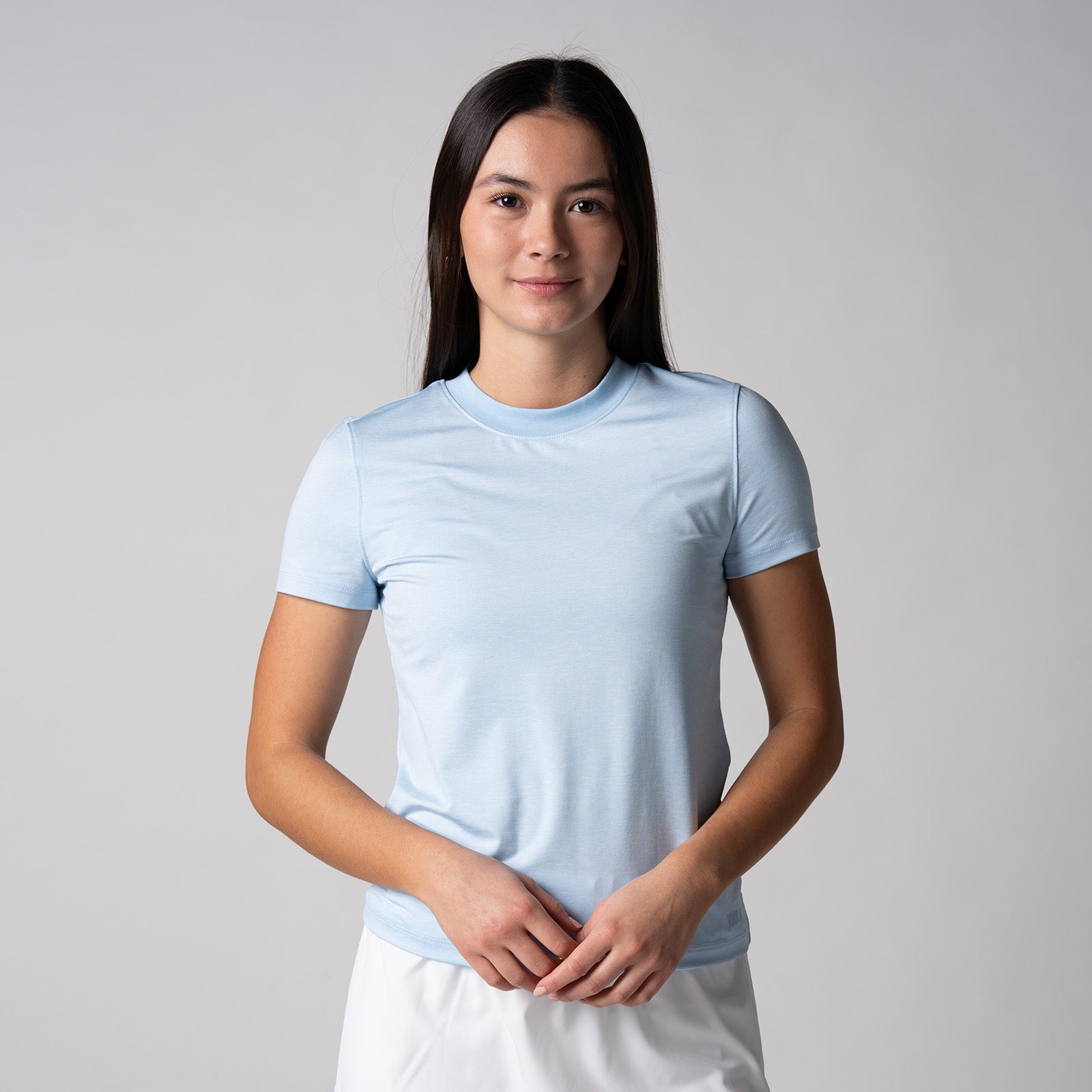 Gray background, female model wearing a JOOLA women's club short sleeve, blue breeze.