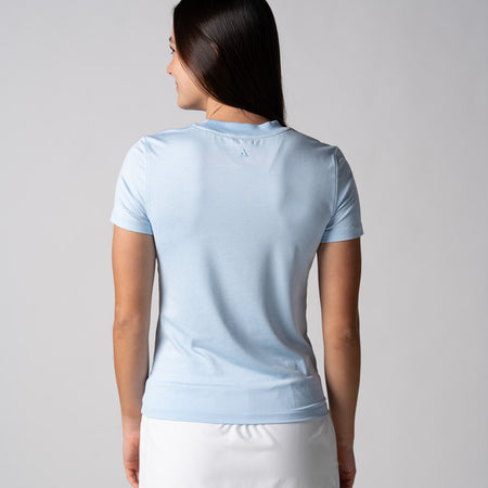 Gray background, image of the back of a female model wearing a JOOLA women's club short sleeve, blue breeze.
