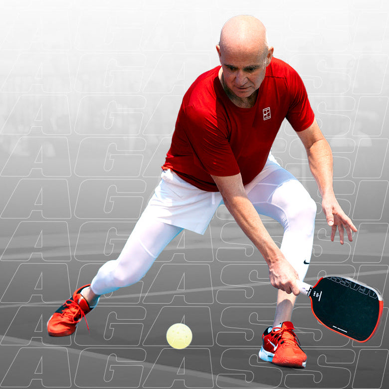 Vertical image of Andre Agassi about to hit the pickleball with the Agassi pickleball paddle.
