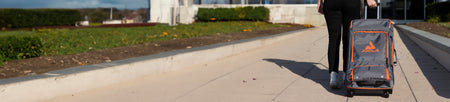 Horizontal banner image of someone wheeling away a JOOLA travel suitcase.