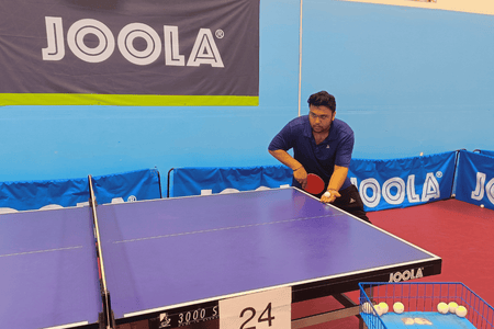 Coach Subhum Kundu demonstrates a strong table tennis serve.