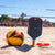 Beach volleyball ball and JOOLA Rally Rocket pickleball paddle on sand with volleyball net in background