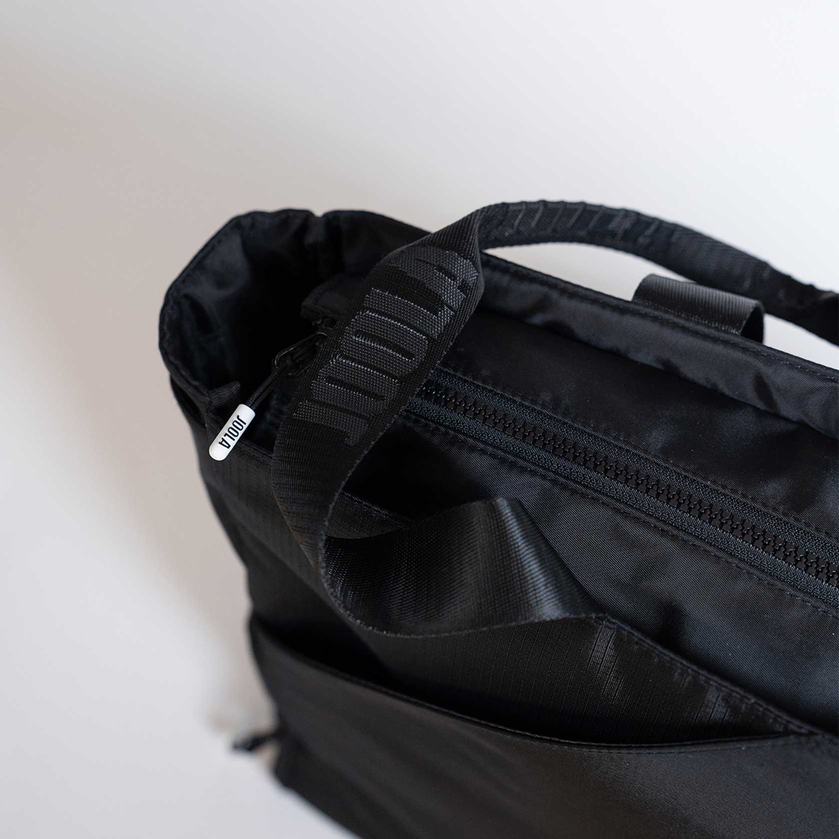 Close-up of a black backpack with visible branding on a light background