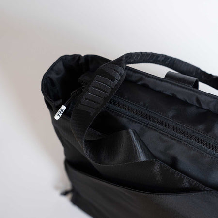 Close-up of a black backpack with visible branding on a light background