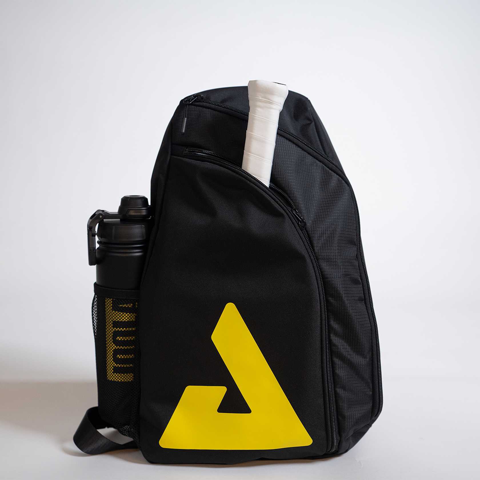 Black sling bag with yellow logo and water bottle on a light gray background