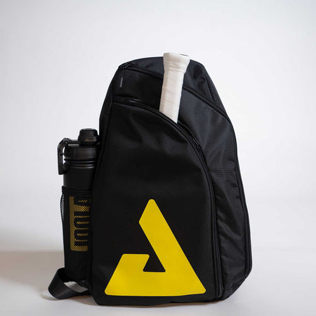 Black sling bag with yellow logo and water bottle on a light gray background