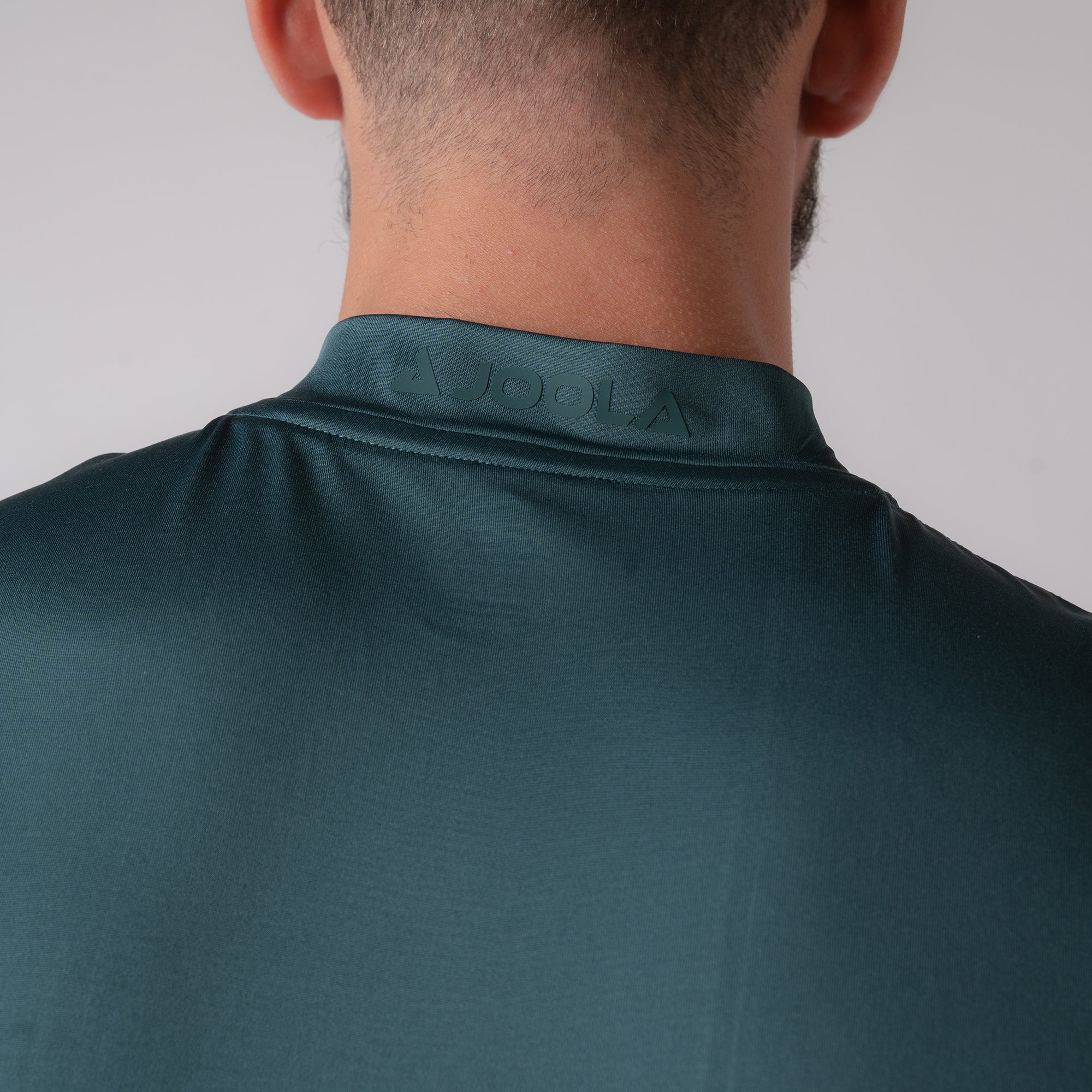 Close up image of the back of a JOOLA Men's Court Polo in club green. The JOOLA logo is on the neck.