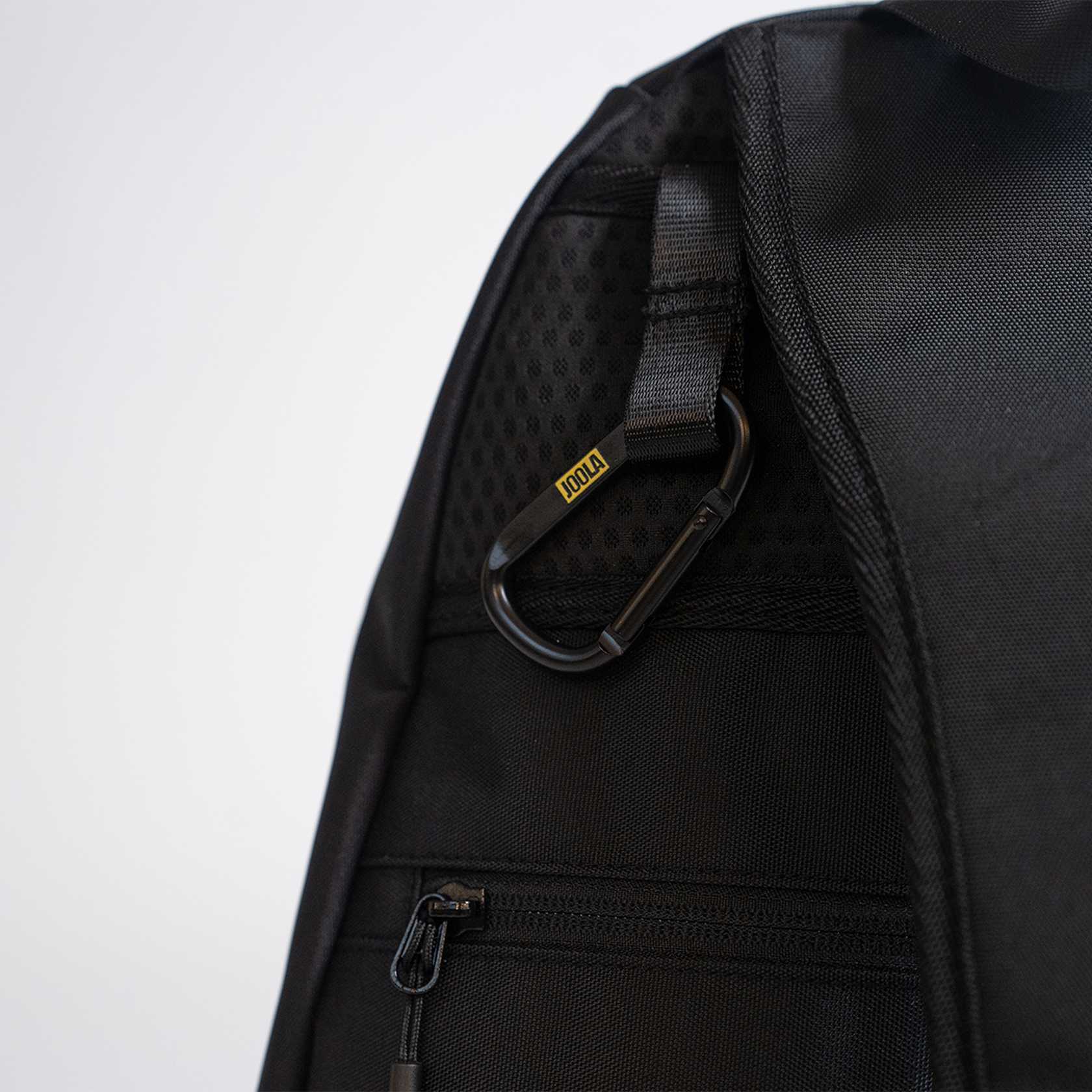 Black backpack with a JOOLA branded carabiner and zipper on a light gray background