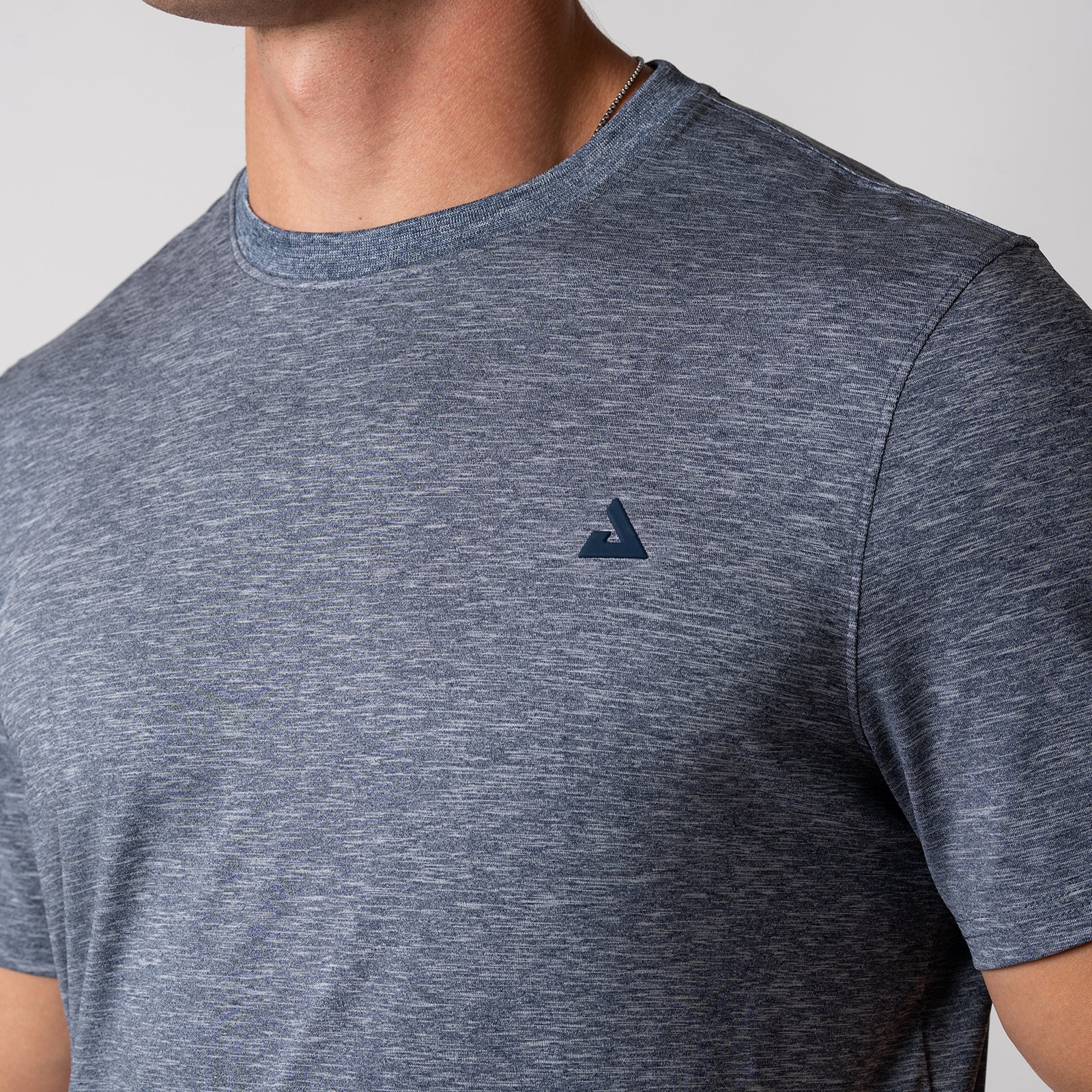 Close up of the JOOLA Trinity logo on the JOOLA Men's Club Short Sleeve Shirt, Navy Heather.