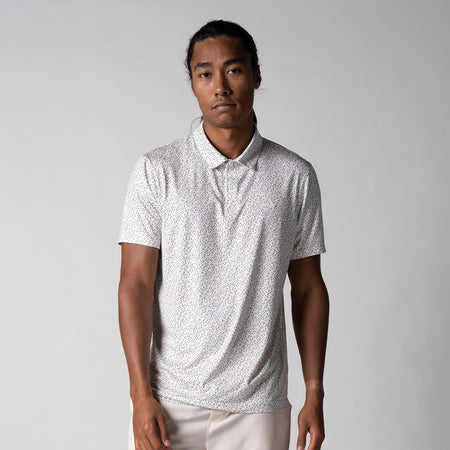 Gray background, image of a male model wearing the JOOLA Men's Club Printed Polo, Safari leopard pattern.