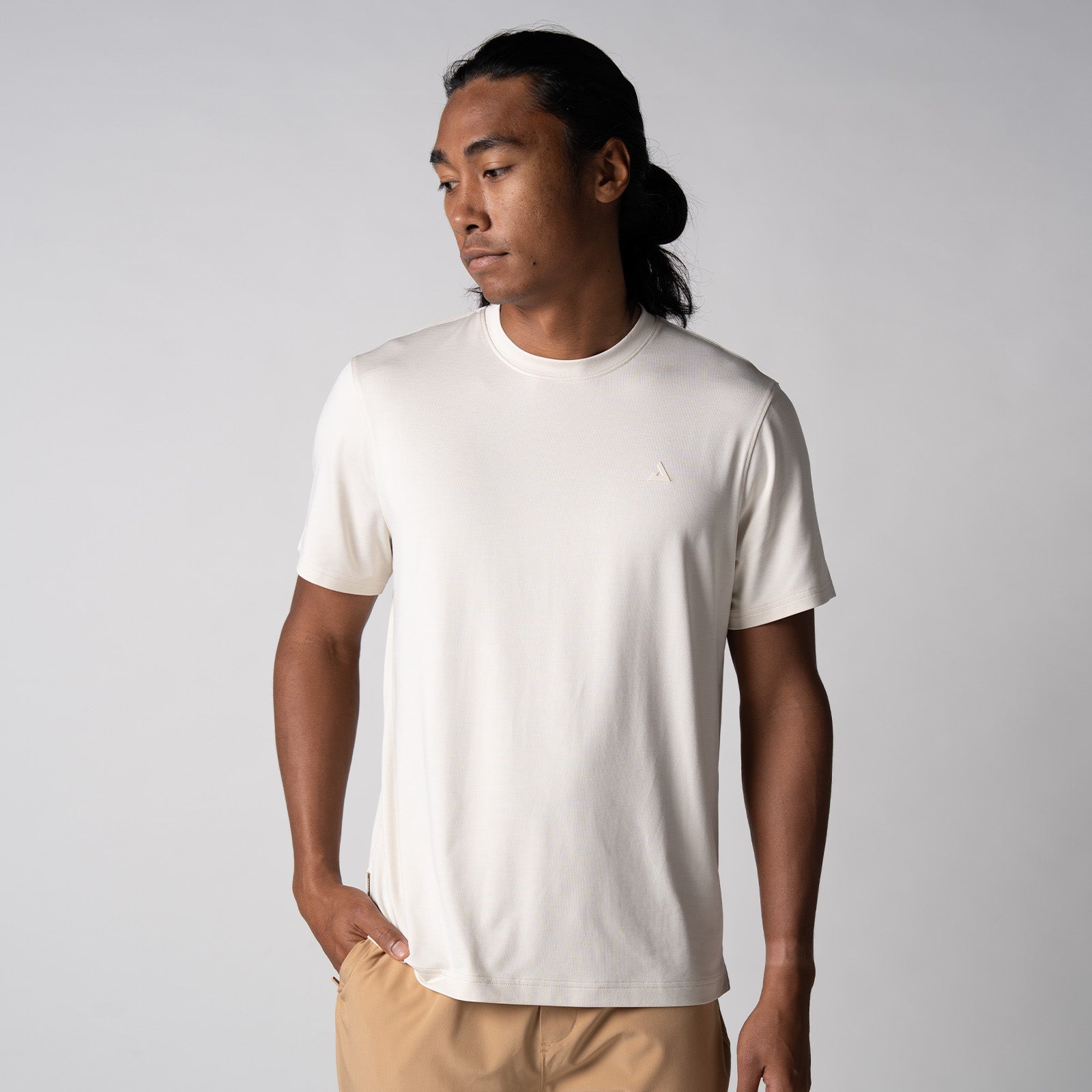 Gray background, image of a male model wearing a JOOLA Men's Club Short Sleeve shirt, sandstone color.