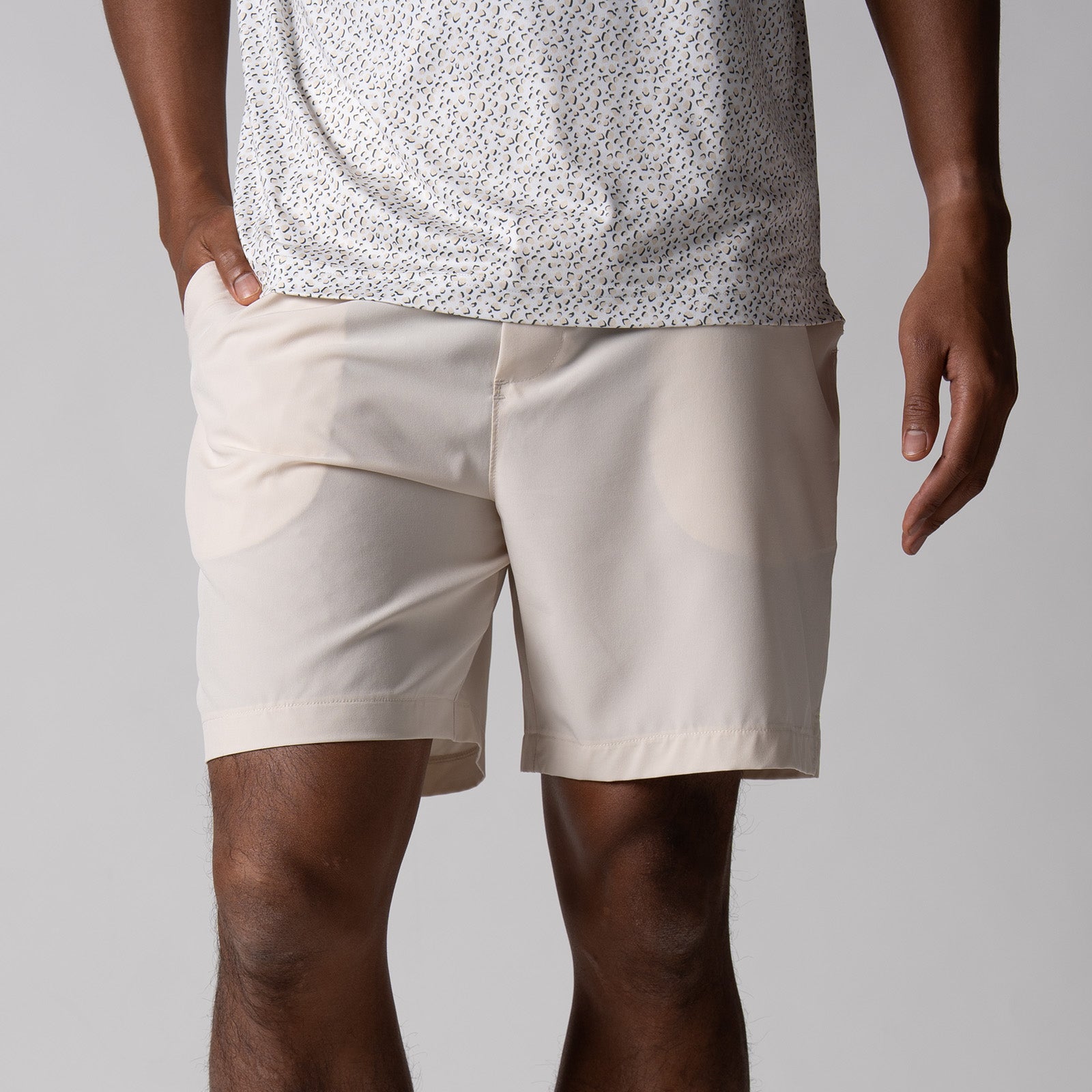 Gray background, close up image of a male model wearing a pair of JOOLA men's club shorts, sandstone color.