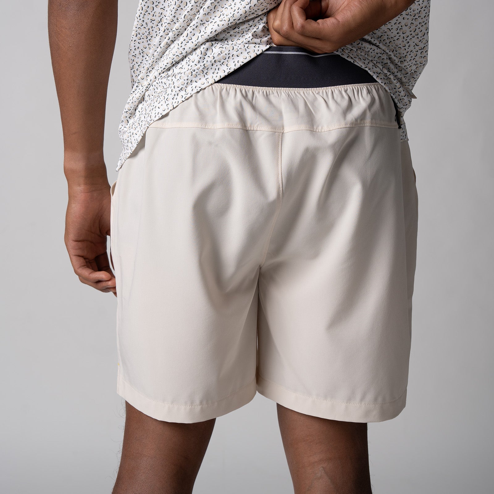 Close up image of the back of a pair of JOOLA men's club shorts, sandstone color.