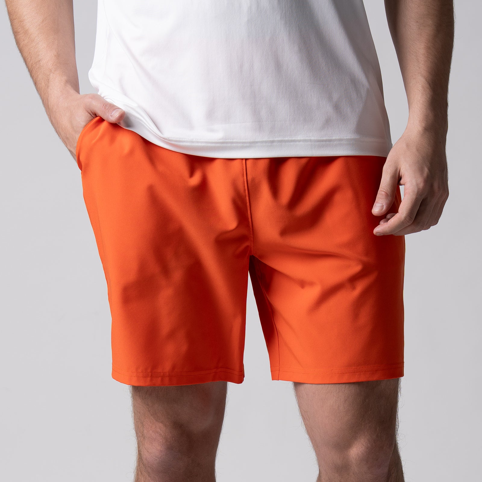 Gray background, close up image of a male model with his right hand in a pair of JOOLA men's woven shorts, 7-inch, poppy red color.