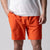 Gray background, close up image of a male model with his right hand in a pair of JOOLA men's woven shorts, 7-inch, poppy red color.