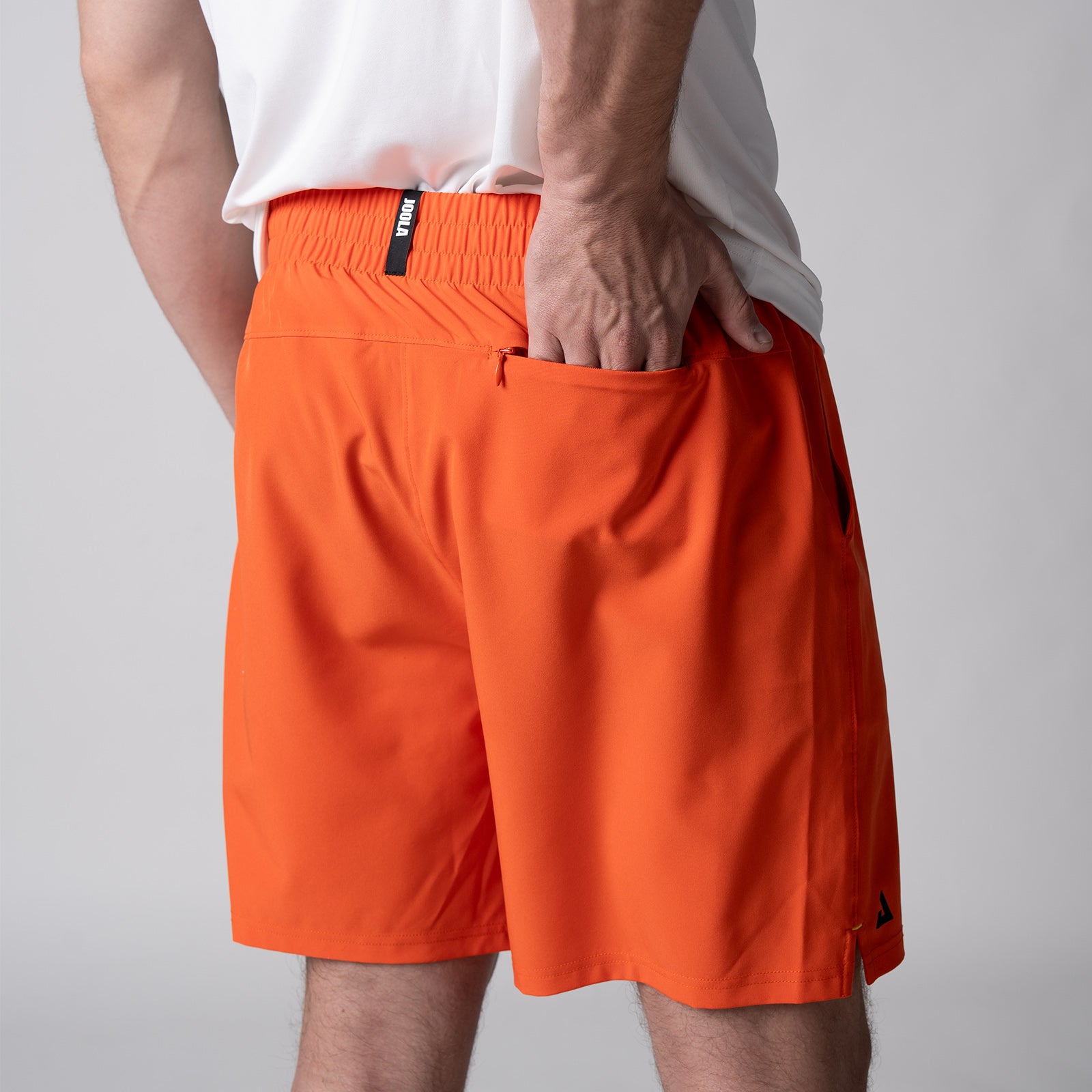 Gray background, close up image of the back of a male model who is wearing the JOOLA Men's Woven Shorts, 7-inch inseam, poppy red color.