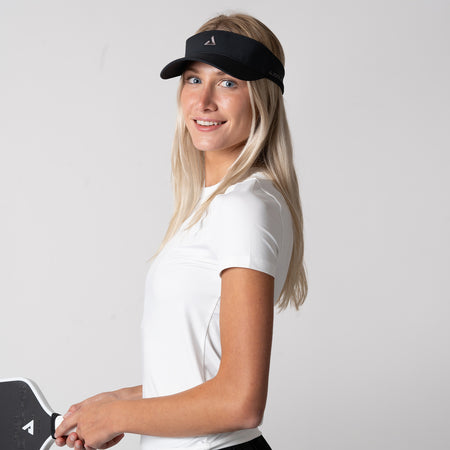 Image of a female model wearing a JOOLA trinity visor and a JOOLA women's club short sleeve shirt, white.