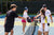 Group of four pickleball players doing a paddle tap at the net on a pickleball court.
