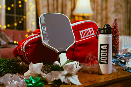Festive JOOLA Holiday pickleball bundle, featuring a JOOLA Perseus Pro IV, JOOLA Water Bottle and JOOLA Red and White Elite Tour bag.