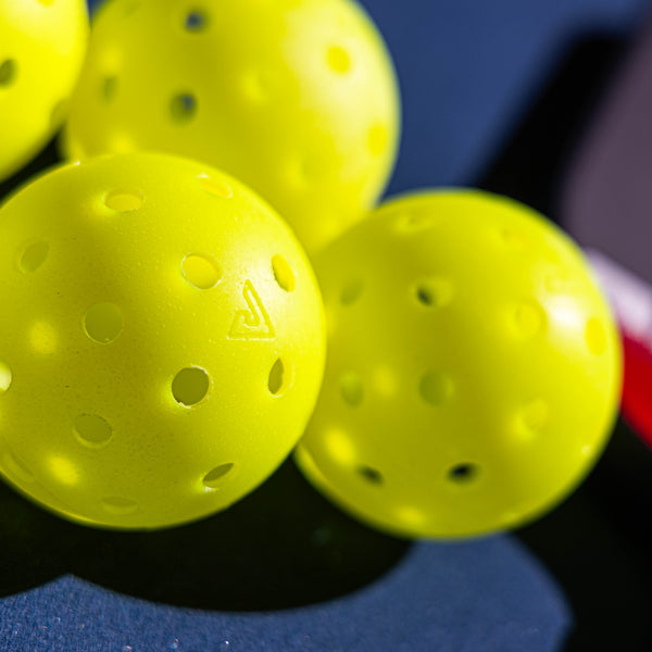 Close-up of yellow pickleball balls with a blue background.