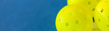 Horizontal banner image showing a close up of three JOOLA HC-40 pickleballs.