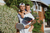 Man holding a child on his shoulders with JOOLA R4LLy pickleball paddles, outdoors.