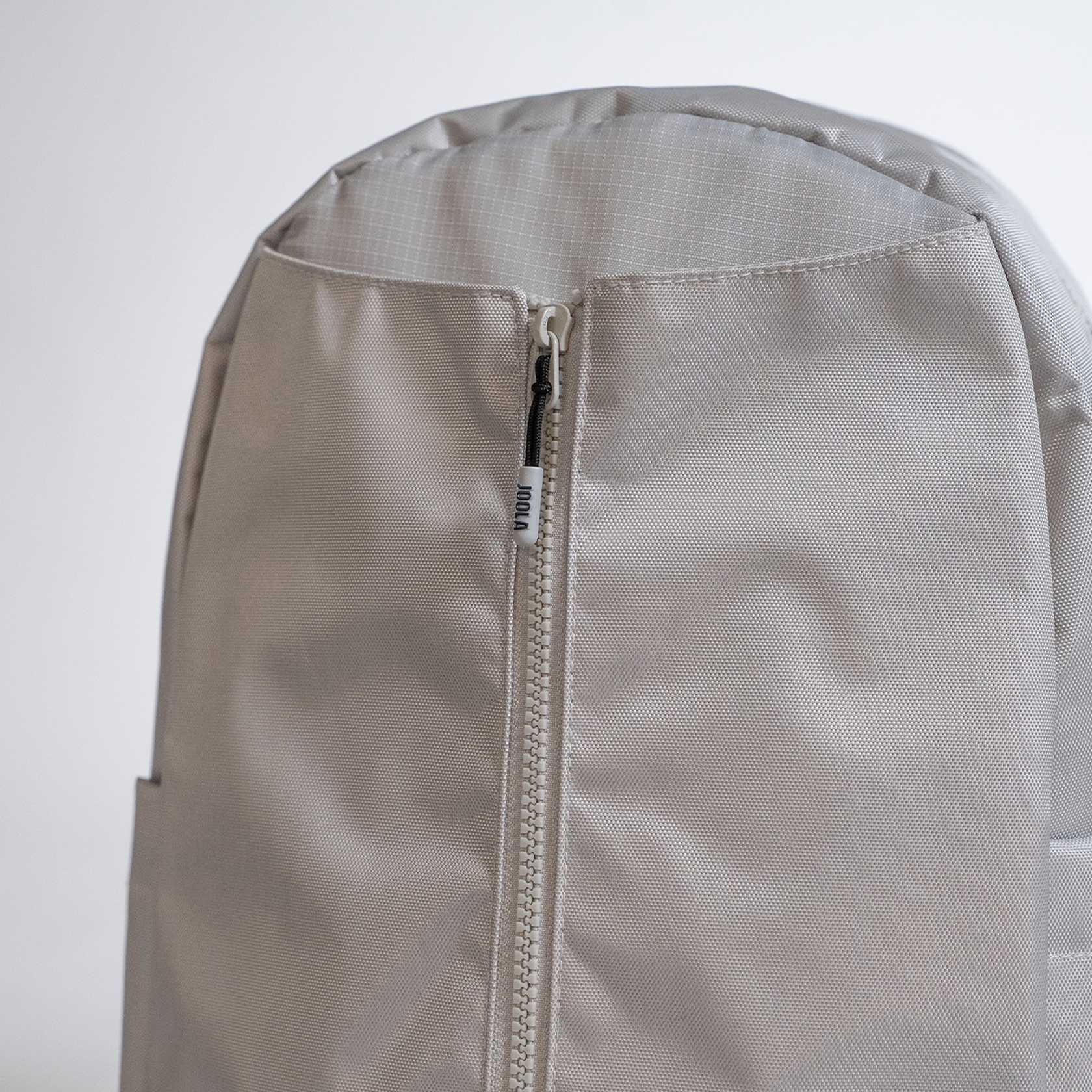 Close-up of a gray JOOLA backpack with a zipper on a light gray background