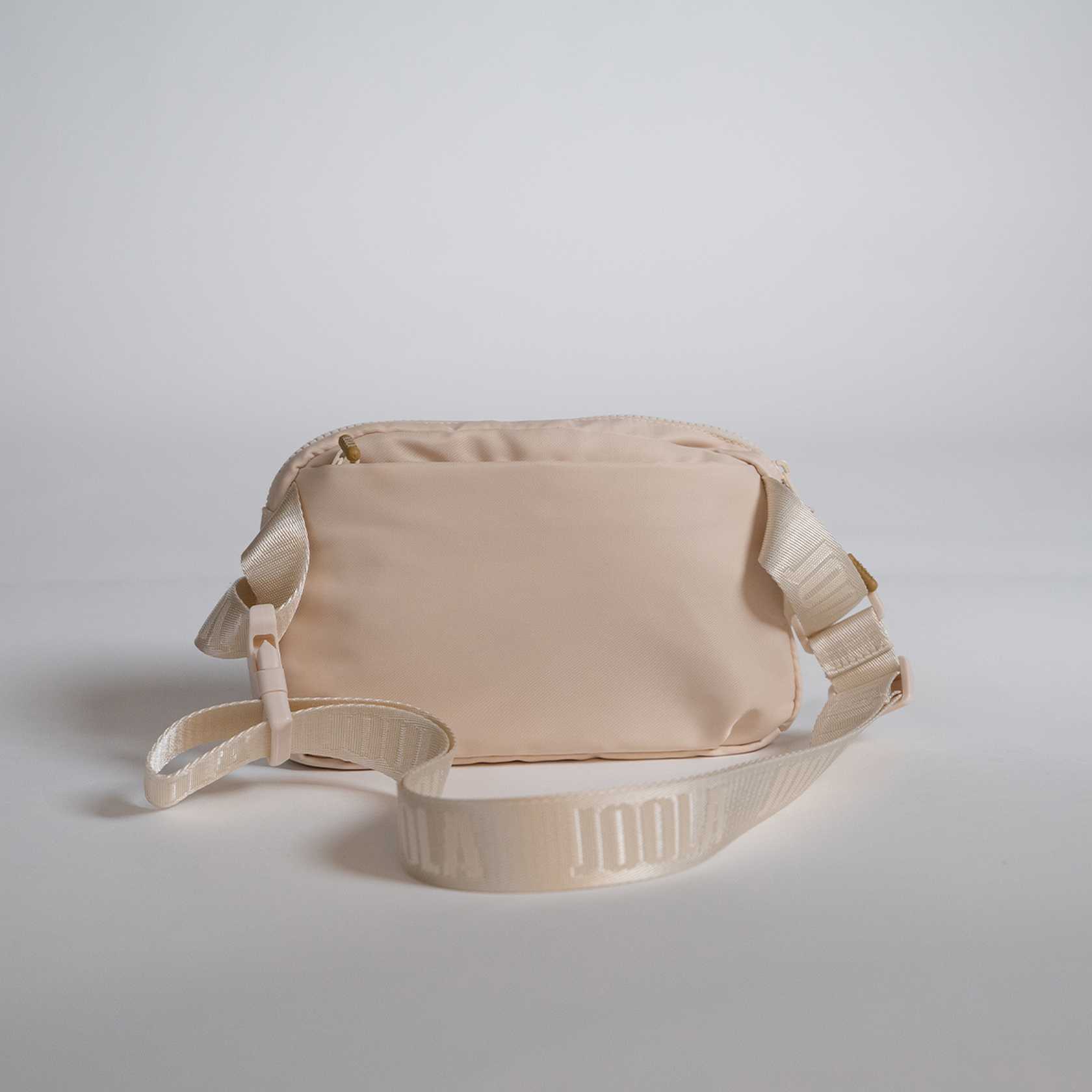 Beige waist bag with a strap on a light gray background.