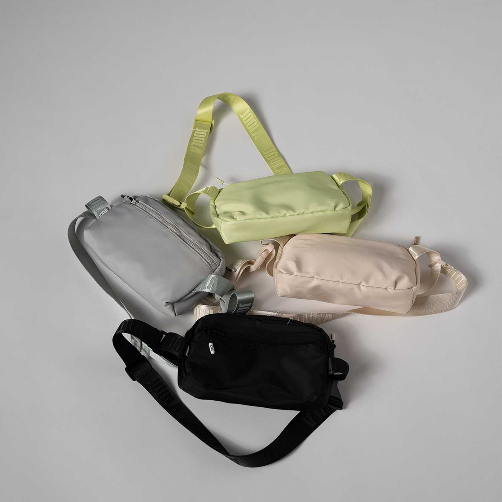 Four JOOLA waist bags in black, beige, green, and gray on a light gray background