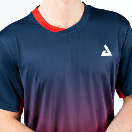 White background, close up on a JOOLA Trinity Logo on a men's JOOLA Competition table tennis shirt, with a half blue and red neckline.
