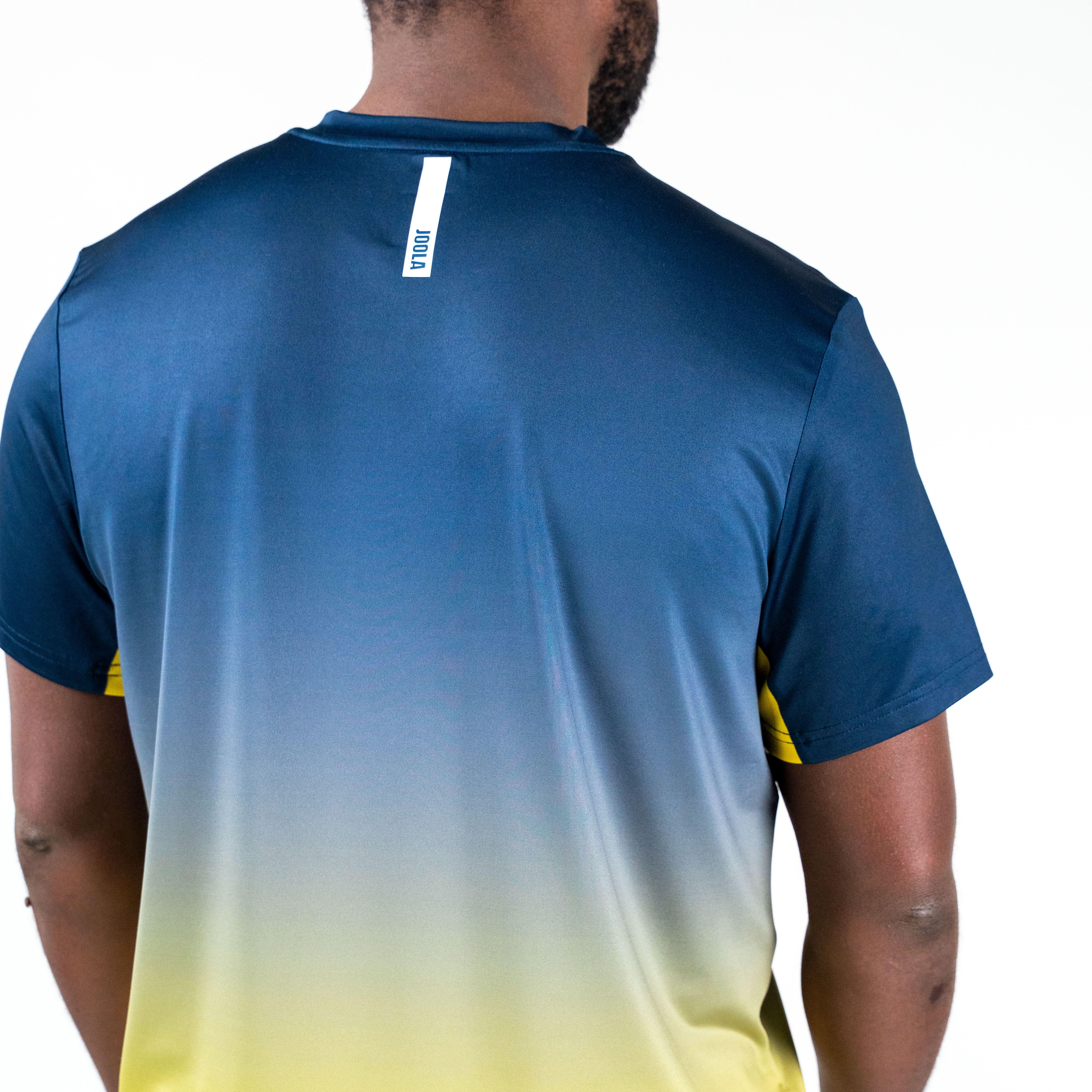 White background, product image showing the back of a JOOLA Men's Competition table tennis shirt, yellow and blue colorway.