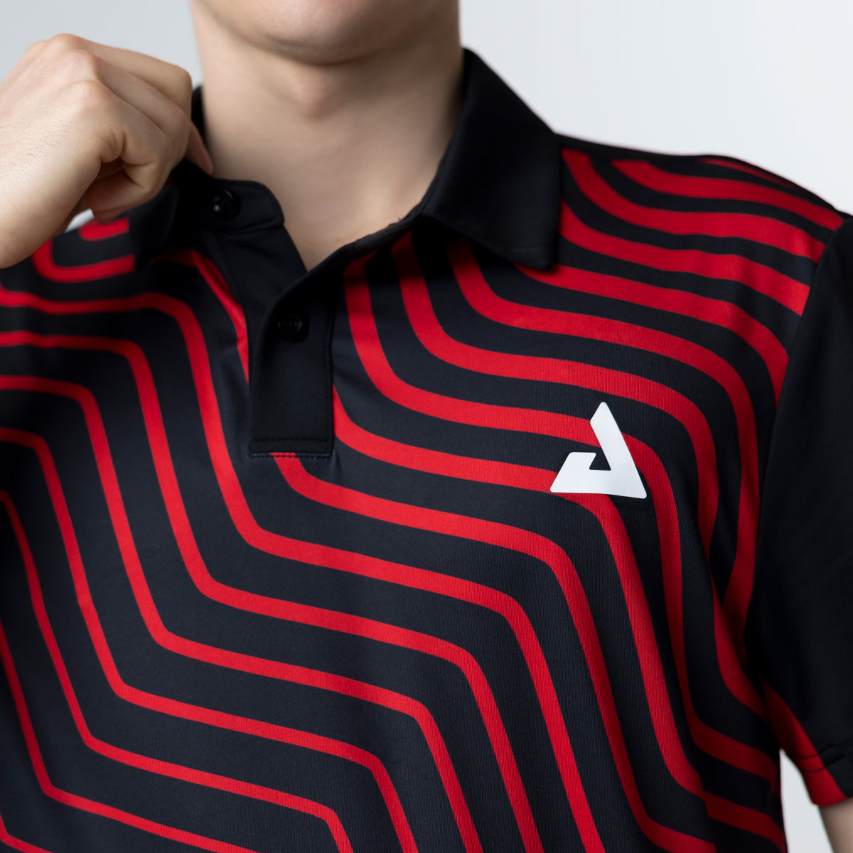 Person wearing a black and red striped polo shirt with a white JOOLA Trinity logo on a light gray background