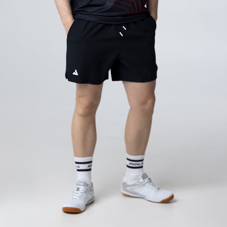 Gray background, image of a mail model wearing a pair of JOOLA Shorts (Black and white).