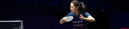 Woman playing table tennis with a dark background.