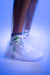 Purple gradient background, product image showing a models wearing a pair of white and green JOOLA TT SM4SH table tennis shoes.