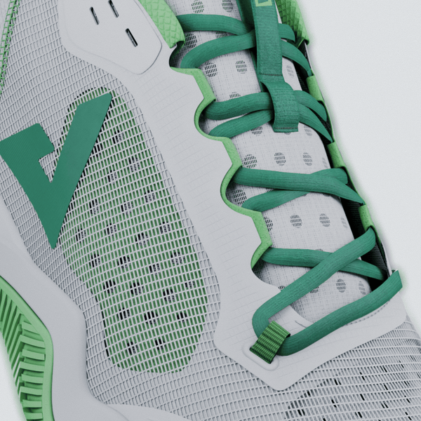 Close-up of a green and white athletic shoe with mesh design.