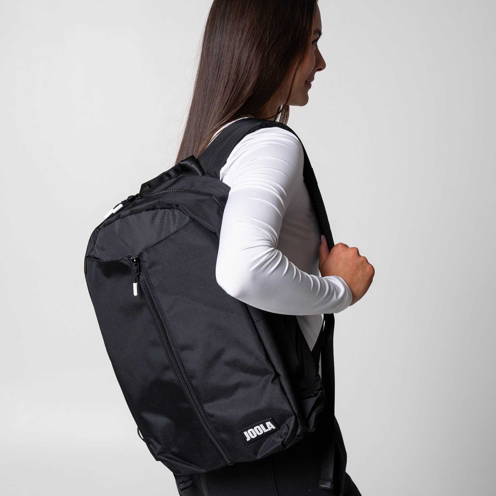 Gray background, image of a female model with the JOOLA Backpack over her shoulder.