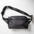 Gray background, product image of a black JOOLA Belt Bag.