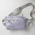 Gray background, product image of a JOOLA Belt Bag, purple with a gray handle.