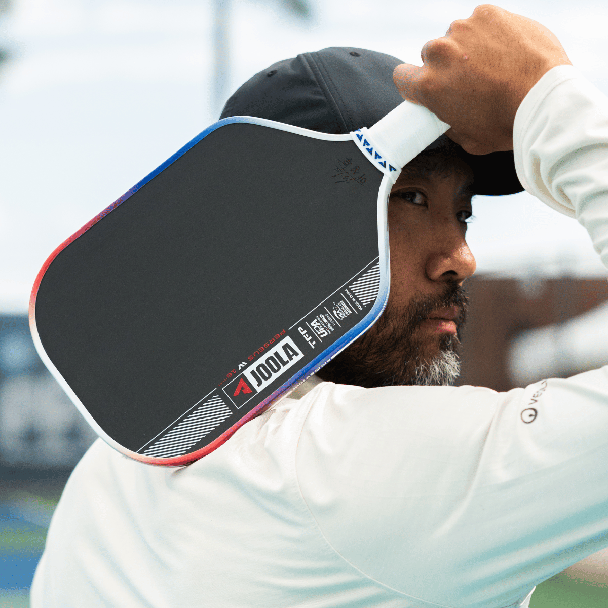 JOOLA Pro Chuck Taylor holding his signature Perseus Pro IV pickelball paddle up by his head.