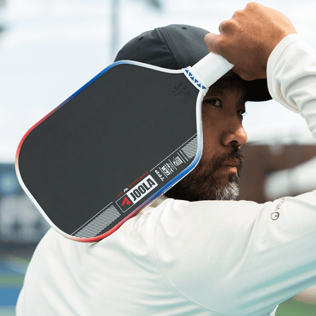 JOOLA Pro Chuck Taylor holding his signature Perseus Pro IV pickelball paddle up by his head.