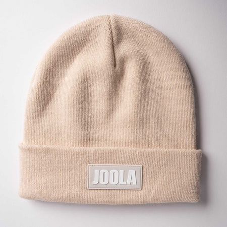Gray background, product image of a sandstone colored JOOLA Cuff Beanie.