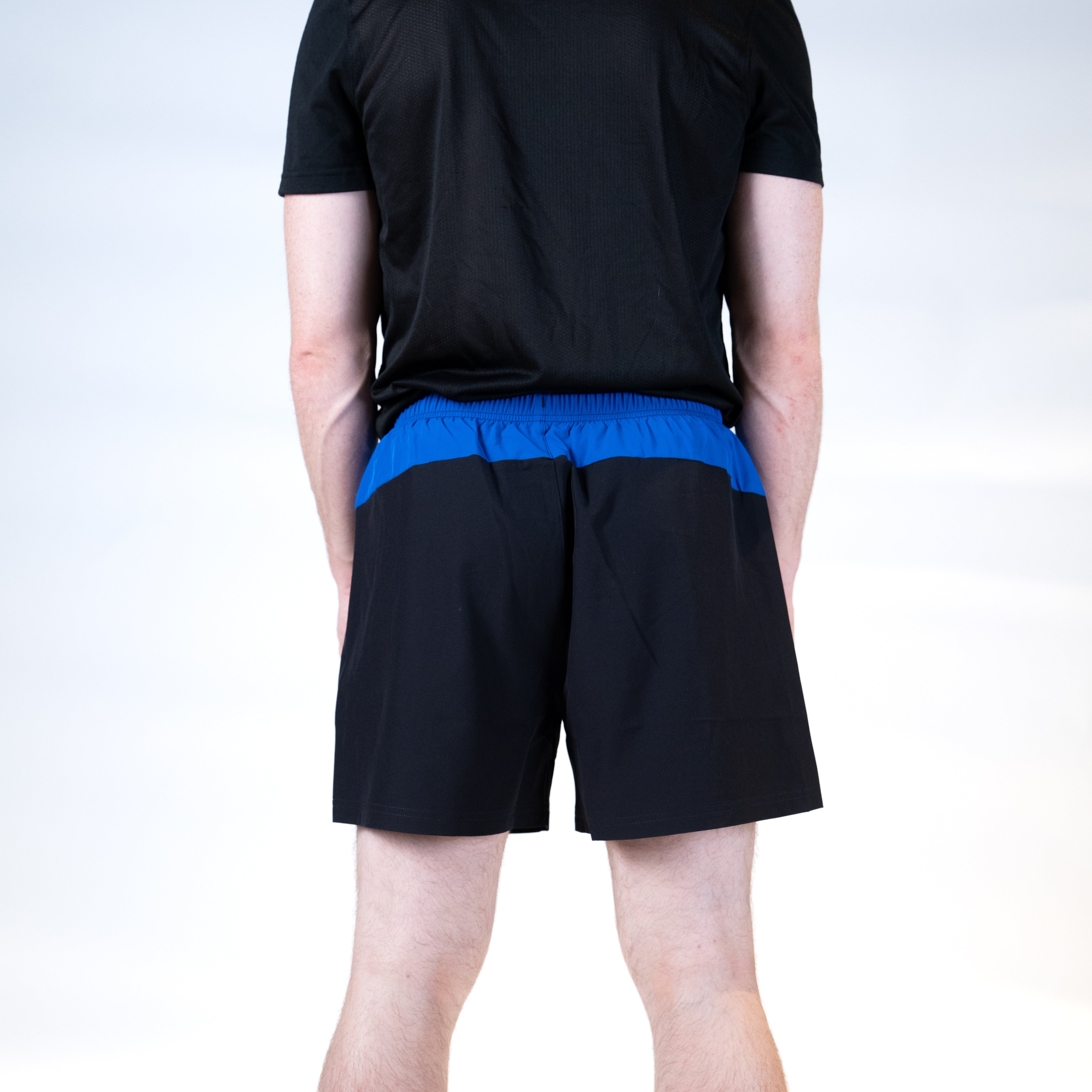 White background, product image showing the rear view of a male model wearing a pair of black and blue JOOLA x Hugo Calderano shorts.