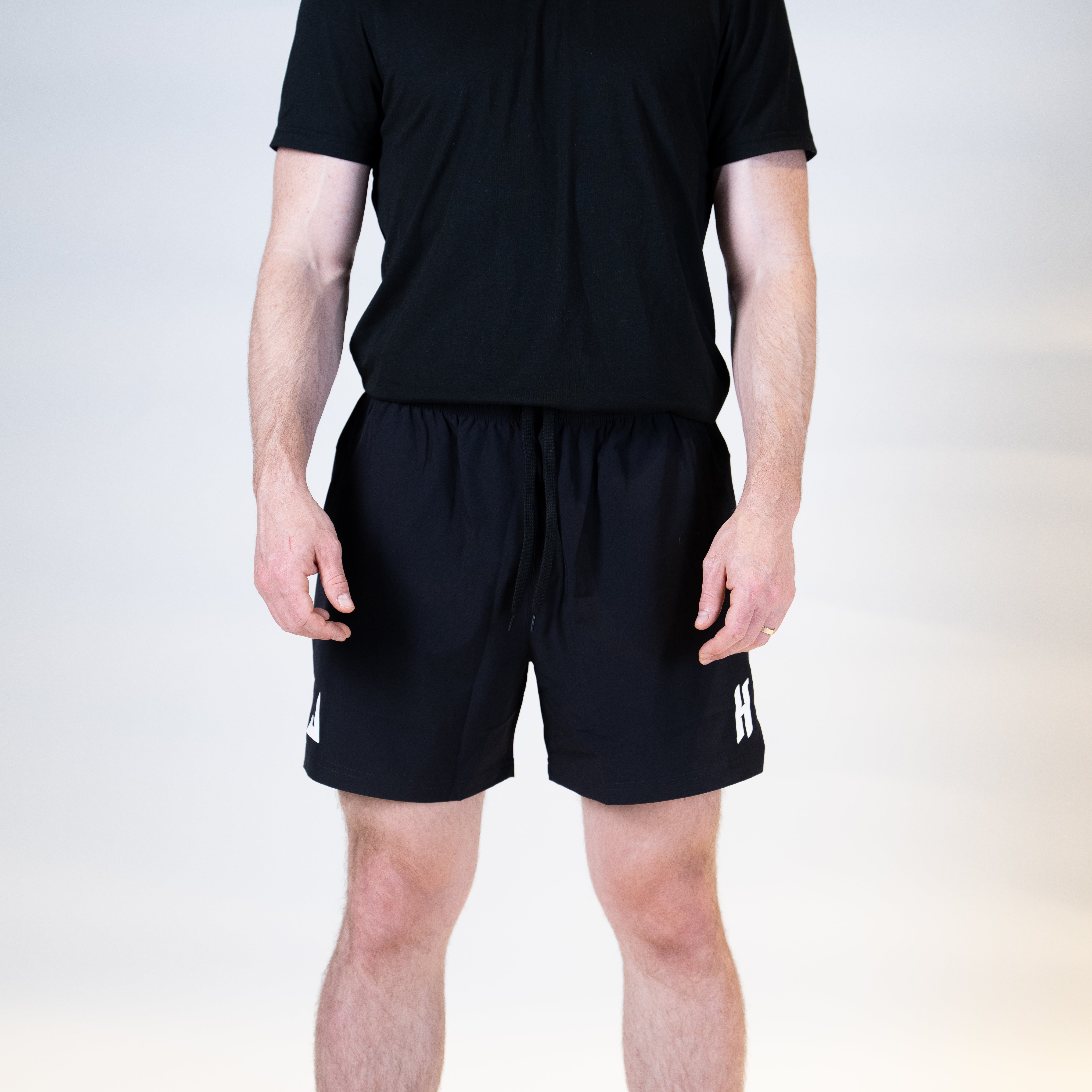 White background, man wearing a pair of JOOLA x Hugo Calderano table tennis shorts, black.