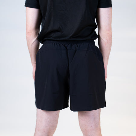 White background, product image showing the rear view of a male model wearing a pair of Hugo Calderano table tennis shorts.