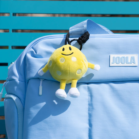 Close up of the JOOLA Plushie Pickleball hanging off a JOOLA puffer bag.
