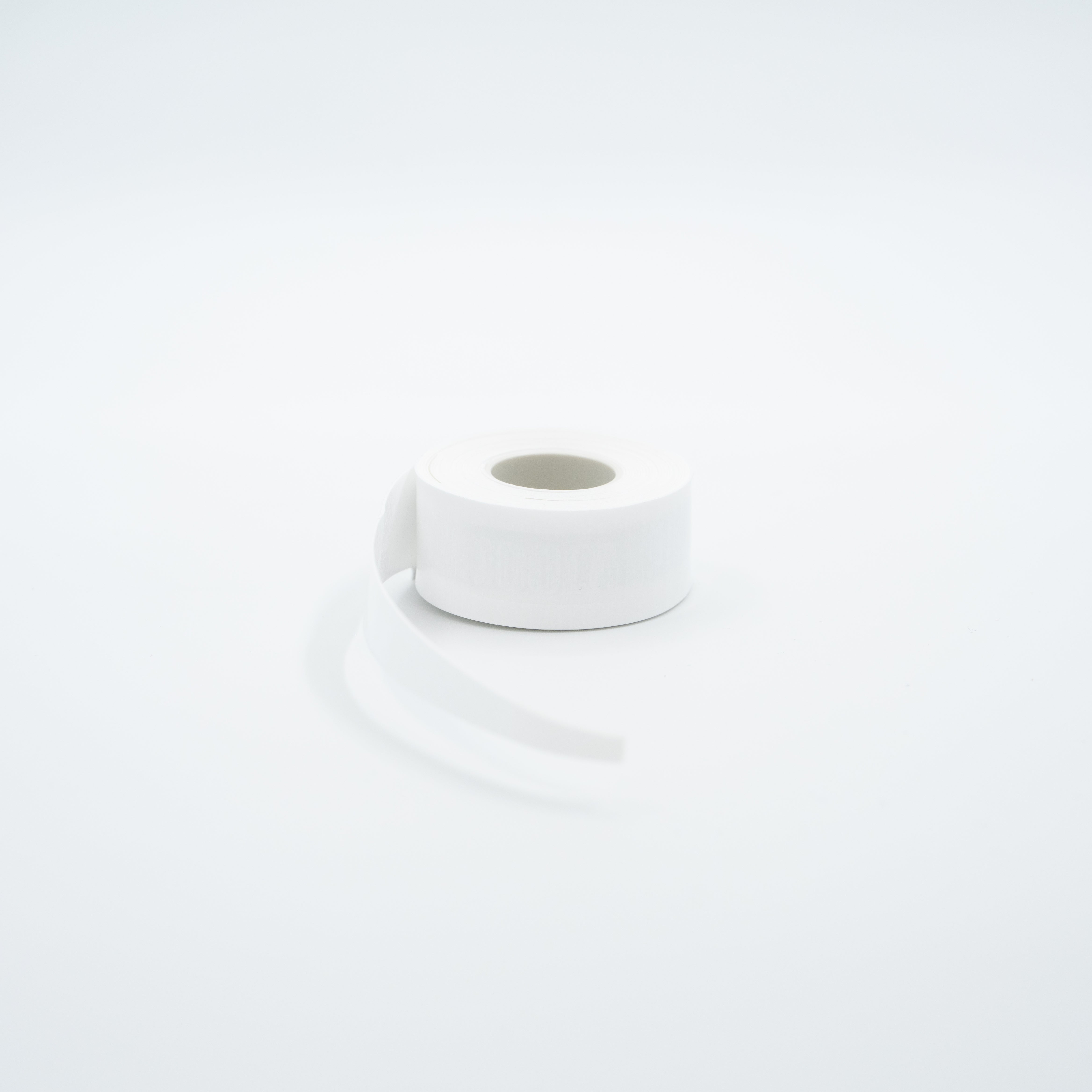 A roll of white JOOLA Overgrip with a strip unrolled, set against a seamless white background.