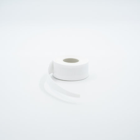 A roll of white JOOLA Overgrip with a strip unrolled, set against a seamless white background.