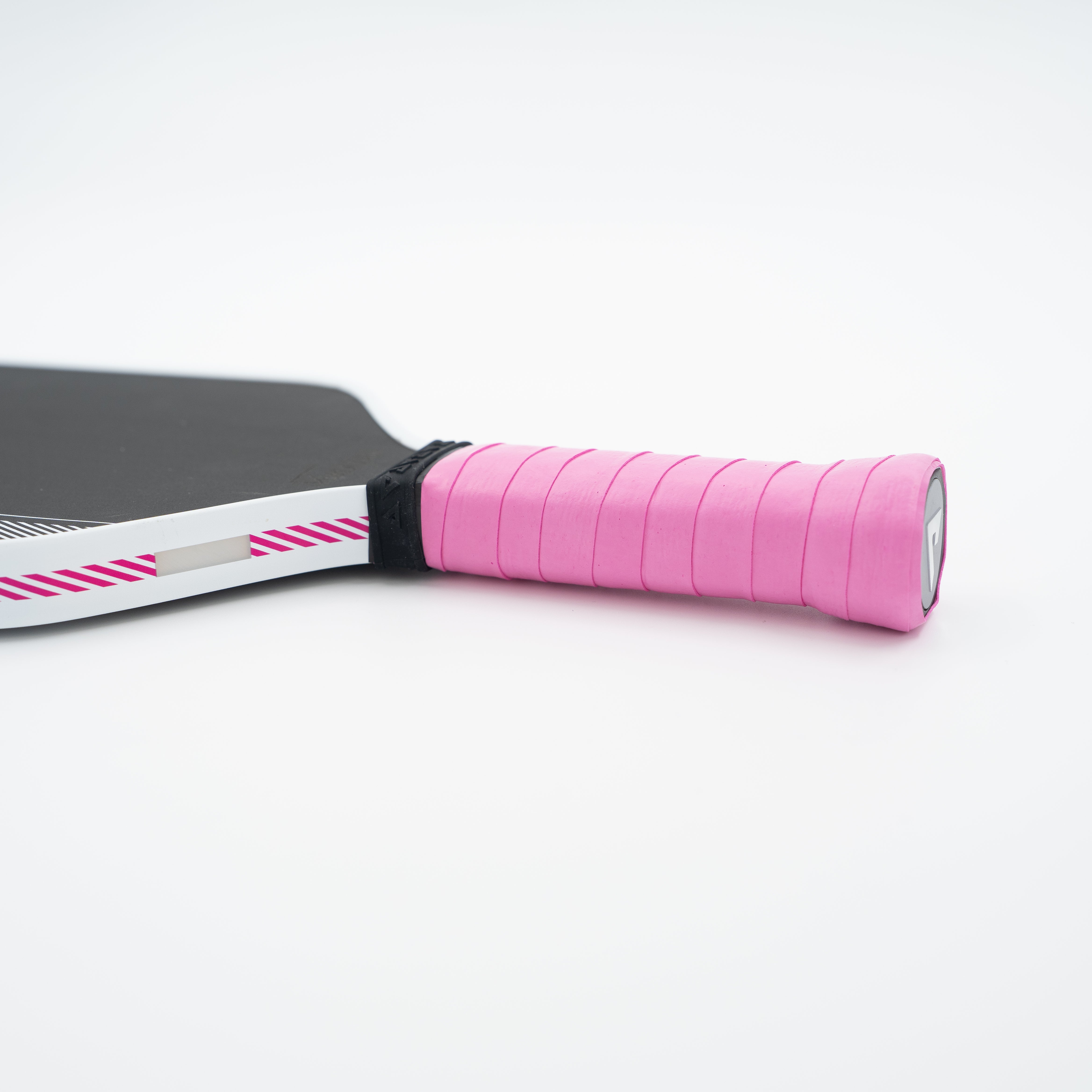 Close-up of a JOOLA paddle handle wrapped in bright pink tape, with part of the black paddle face and a white edge strip featuring pink diagonal stripes visible against a clean white background.